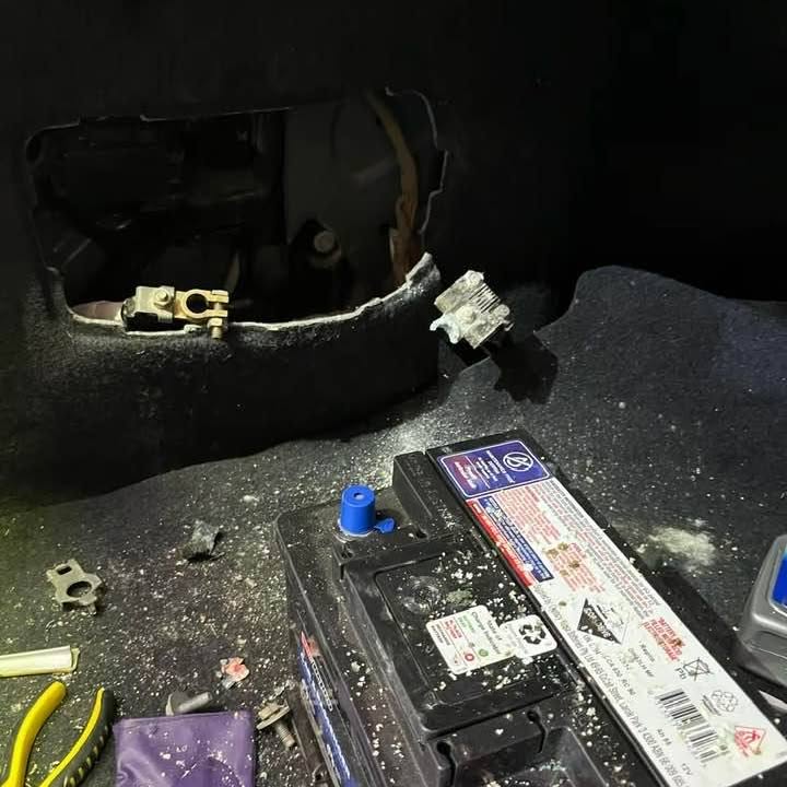 A battery sitting in a corroded battery tray